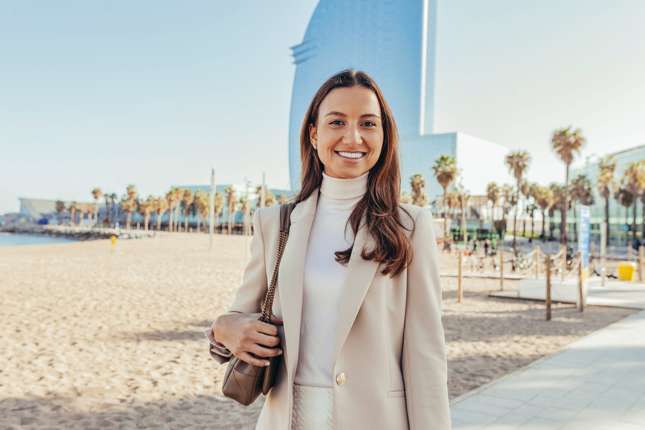 A serene view of Laguna Beach, California, with the Pacific Ocean stretching out to the horizon. The image captures the beautiful coastline, featuring sandy beaches, rocky cliffs, and the deep blue waters of the ocean. In the foreground, palm trees sway gently in the breeze, framing the scene of this popular coastal city for motorcycle enthusiasts.
